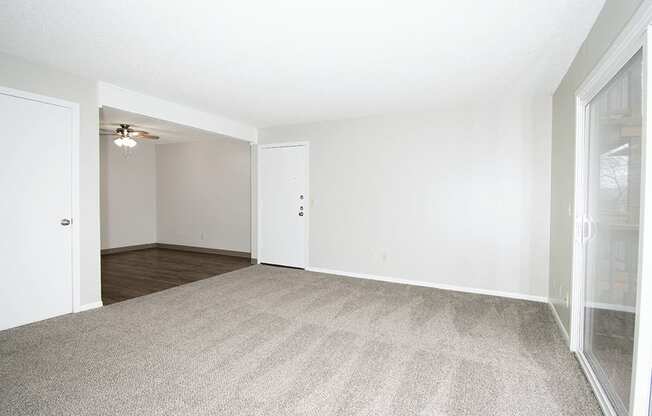 A room with a carpeted floor and a ceiling fan.