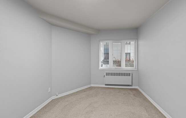 A room with a window and a radiator on the floor.