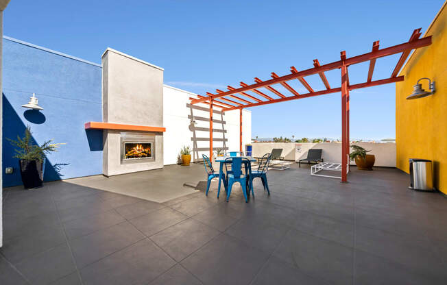 a patio with a blue table and chairs and a fireplace