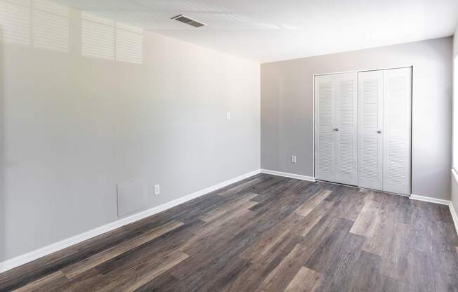 an empty room with wood flooring and white walls and doors