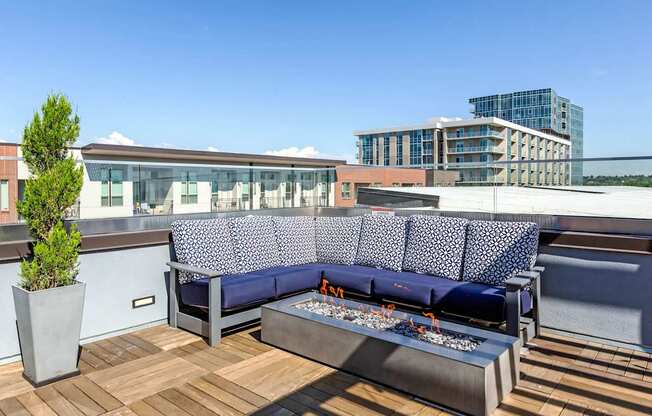 A blue couch with a white patterned cushion is on a wooden deck.