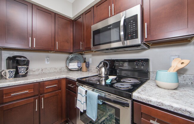 Kitchen with granite countertops stainless microwave and electric stove at St. Croix Apartments in Virginia Beach VA