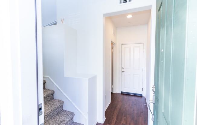 a view of the hallway of a home with stairs and a white door at The Vines at Riverpark, LLC, California, 93036