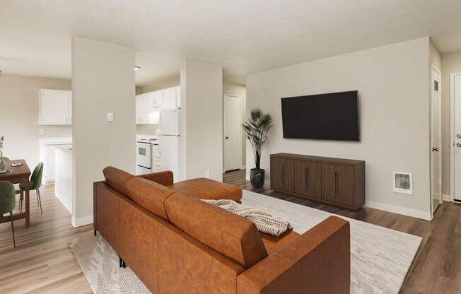 A living room with a brown couch and a flat screen TV mounted on the wall.