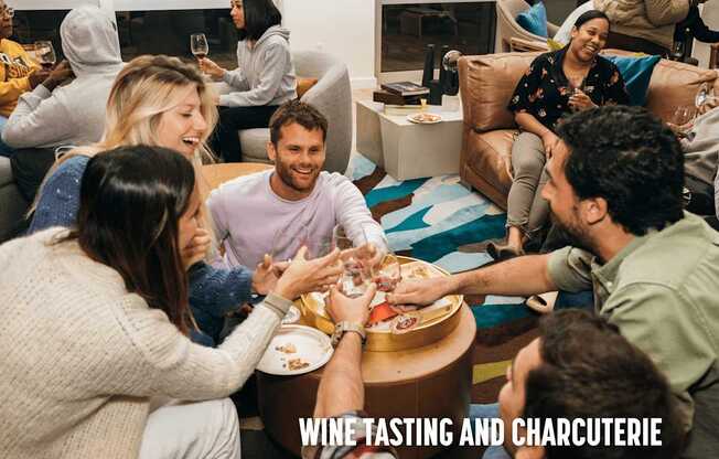 A group of people are gathered around a table for a wine tasting and charcuterie event.