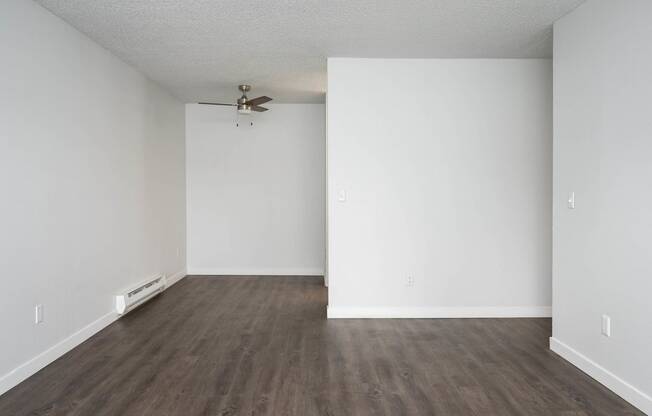 an empty living room with white walls and a ceiling fan