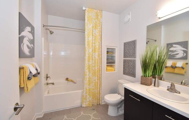 A bathroom with a yellow shower curtain and a white toilet.