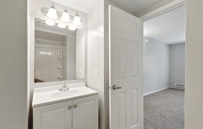 A bathroom with a sink, mirror, and lights.