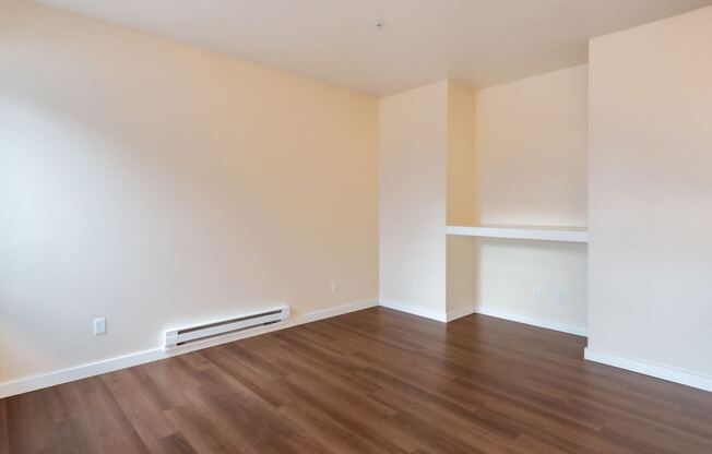 A room with wooden flooring and a wall-mounted air conditioner.