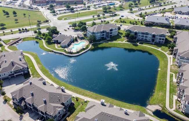A bird's eye view of a residential area with a lake in the middle.