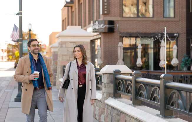 Two people walking on a sidewalk.