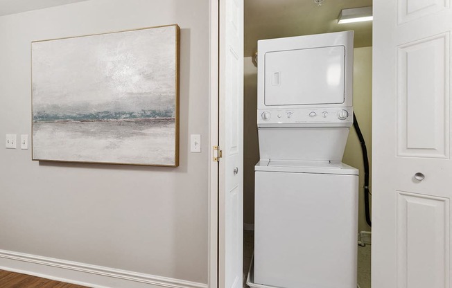 A white fridge in a room with a painting on the wall.