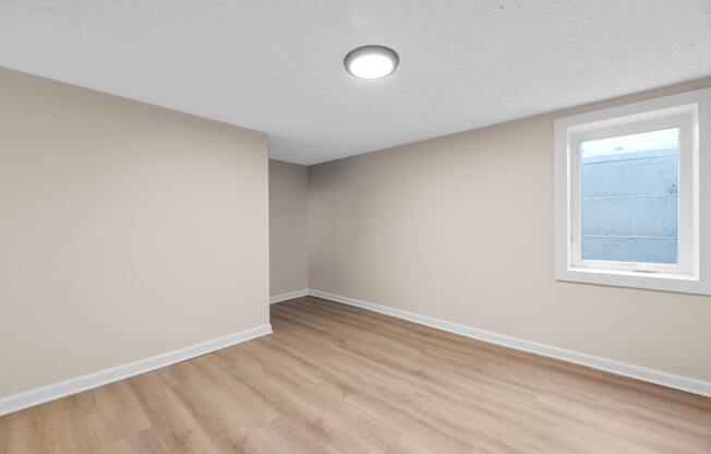 A room with a window and wooden flooring.
