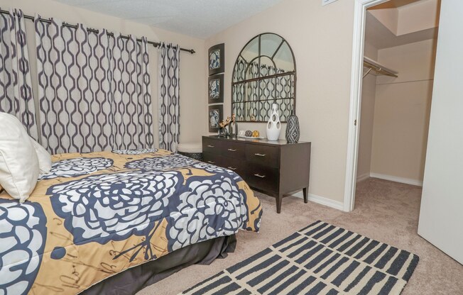 Furnished model apartment bedroom with a bed, nightstand, and a rug at Magnolia Apartments in Shreveport, LA