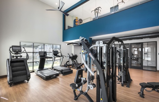 a gym with cardio equipment and weights on a wooden floor