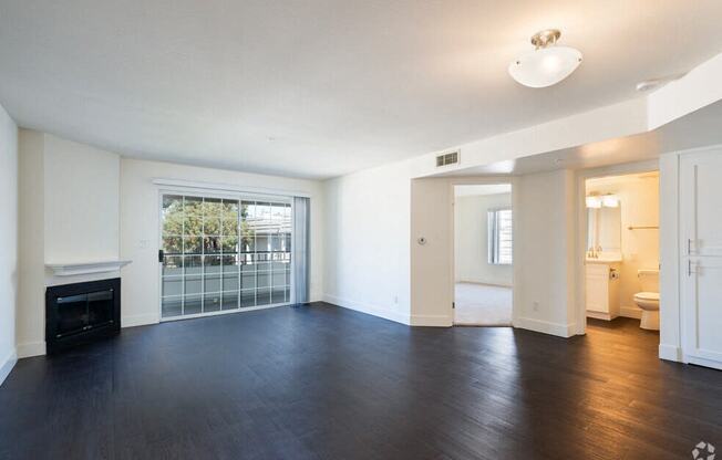 an empty living room with wood flooring and a fireplace