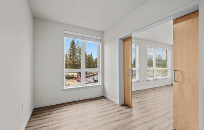 spacious bedroom with sliding barn doors and wood-style plank flooring