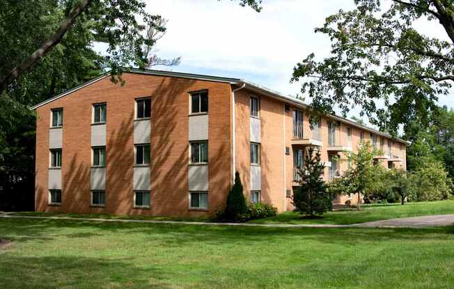 A large brick building with a green lawn in front.