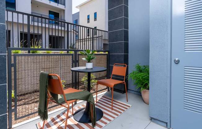 A patio with a table, chairs, and a potted plant.