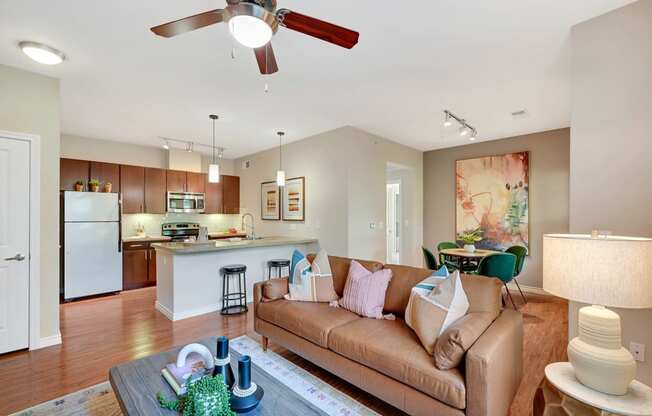 a living room and kitchen with a couch and a ceiling fan