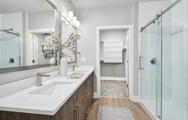 A bathroom with a white sink and a glass shower at The Ashton at East Park Apartments, Kennesaw, Georgia