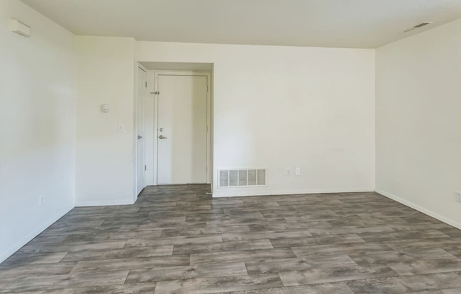 an empty living room with white walls and a grey tile floor