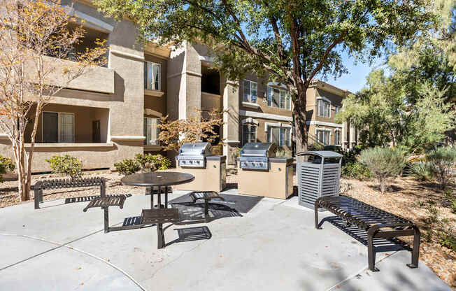 A patio with a table and chairs is surrounded by trees and apartment buildings.