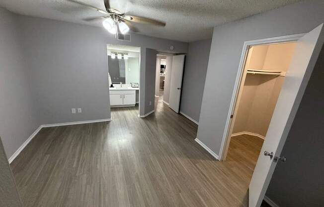 A room with a ceiling fan and light fixture, and a doorway leading to another room.