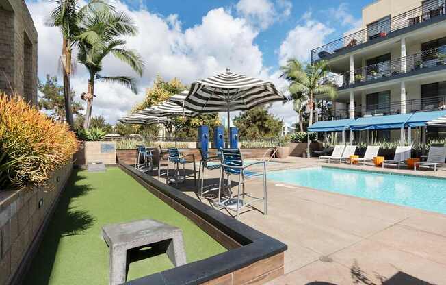 A pool area with a green pool mat and a striped umbrella.