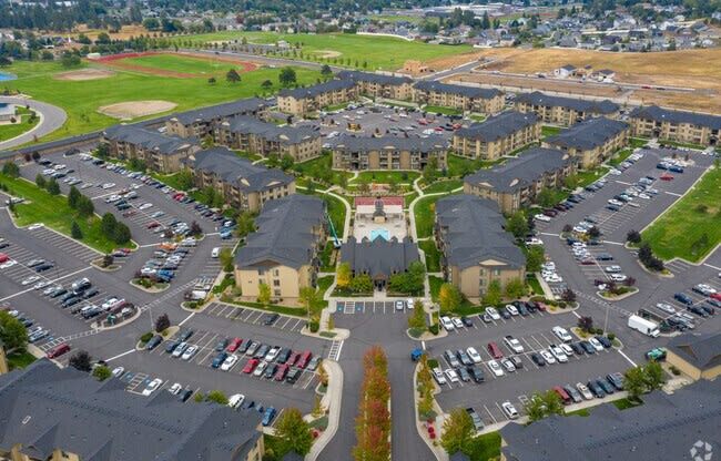 An aerial view of a large parking lot with several rows of houses in the background