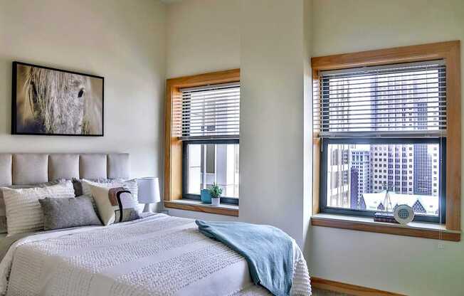 A bedroom with a large bed and a window with blinds.