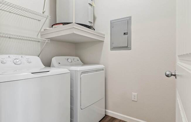 A white dryer and washer are on a shelf in a laundry room.