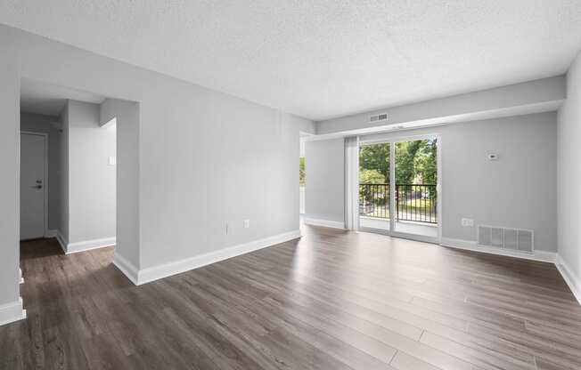 the living room of an empty apartment with wood flooring and a sliding glass door