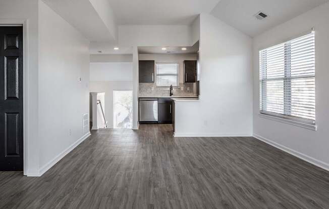 A spacious living room with a kitchen in the background.