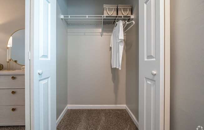 a walk in closet with a white robe hanging on a rack in a bathroom