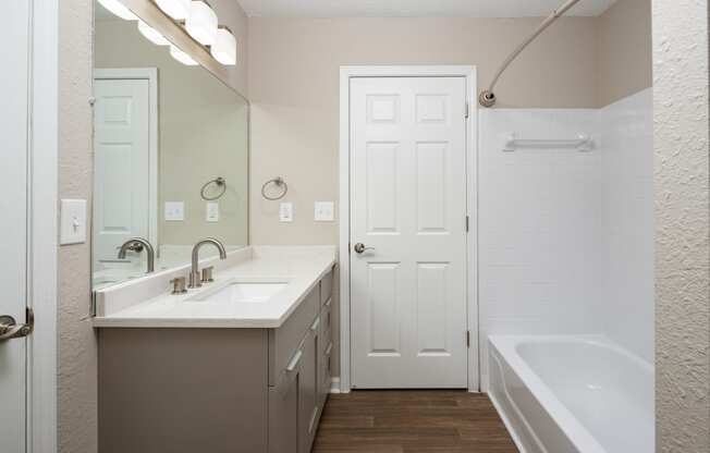 a bathroom with a sink and a tub and a mirror