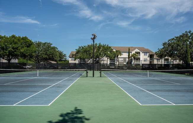 a tennis court with apartments in the background