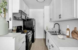 A kitchen with black appliances and white cabinets.