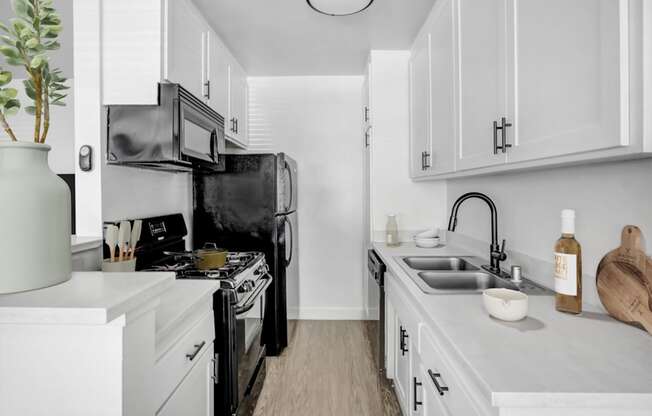 A kitchen with black appliances and white cabinets.