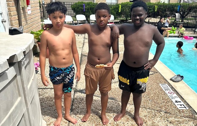 Three boys standing by a pool.