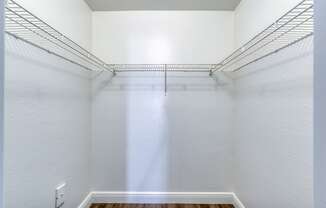 an empty closet with white walls and a wood floor