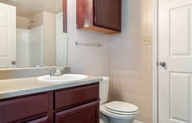 Bathroom with wooden cabinetry and towel bar behind toilet