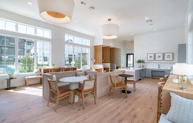 a communal area with tables and chairs and a pool in the background