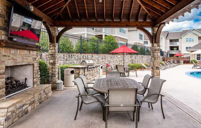 Poolside pavilion with table and six chairs, fireplace and large TV at Riverstone apartments for rent in Macon, GA