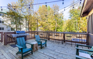 a deck with a picnic table and chairs and a grill