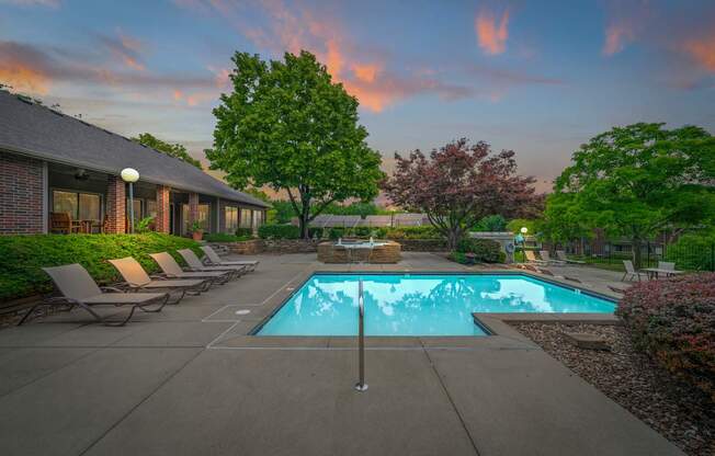 A swimming pool surrounded by lounge chairs and trees.
