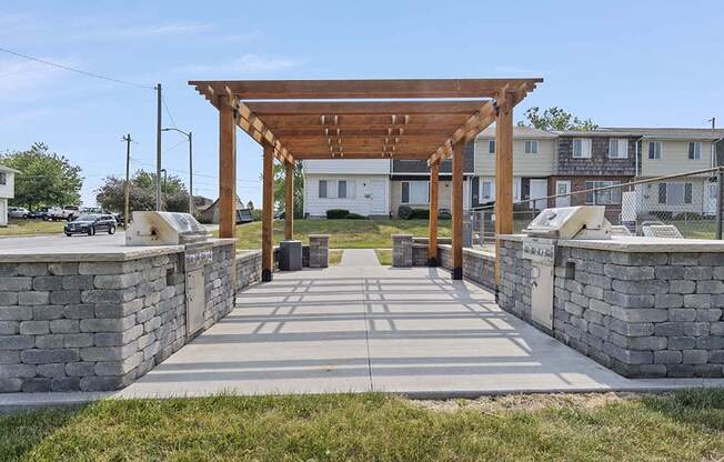 a stone walkway with a wooden pergola