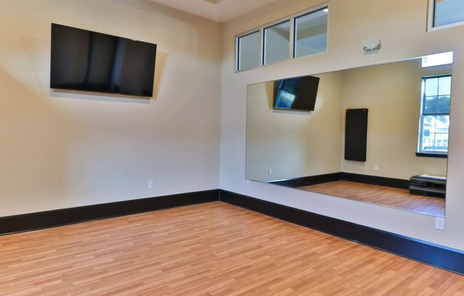 an empty room with wood floors and televisions on the wall