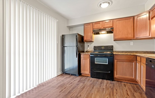 A kitchen with wooden cabinets and a black refrigerator.