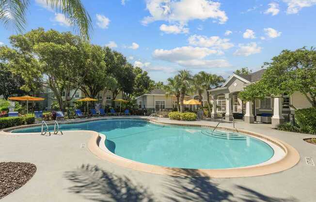 A large swimming pool surrounded by trees and a building in the background.